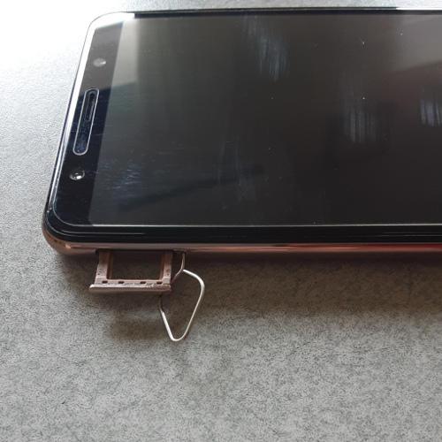 スマートフォンにSIMピンを差し込んでSIMスロットを開ける